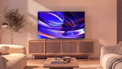 The Sony Bravia 6 OLED TV displaying colorful, abstract imagery from atop a credenza in a dimly lit living room