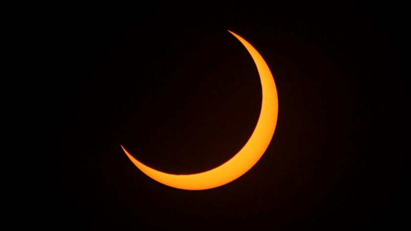 A picture of the sun&#039;s disk almost completely obscured by the moon&#039;s silhouette against a black sky, with only a thin crescent of its lower edge visible.