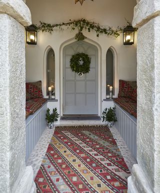 entryway with striped rug and big door and stone lintels
