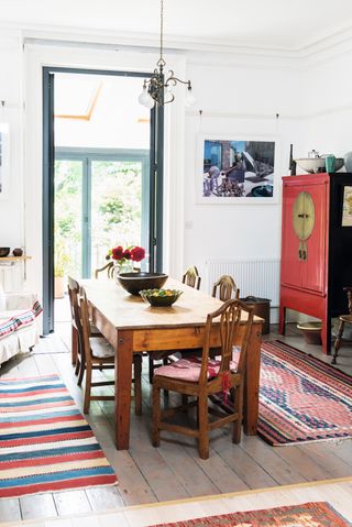 dining room with original wooden floor boards, wooden table and red wardrobe