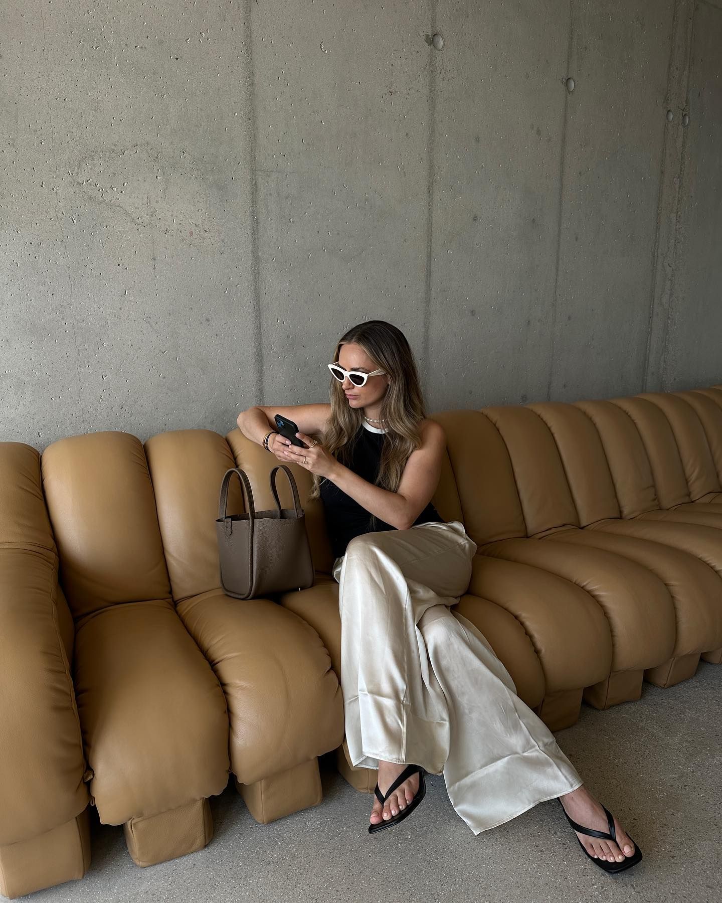@oliviafaeh wears a pair of cream satin trousers with a black and white vest top
