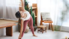 Woman in sportswear bends to one side. She is in a domestic setting