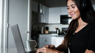 Woman coding on a laptop in her kitchen