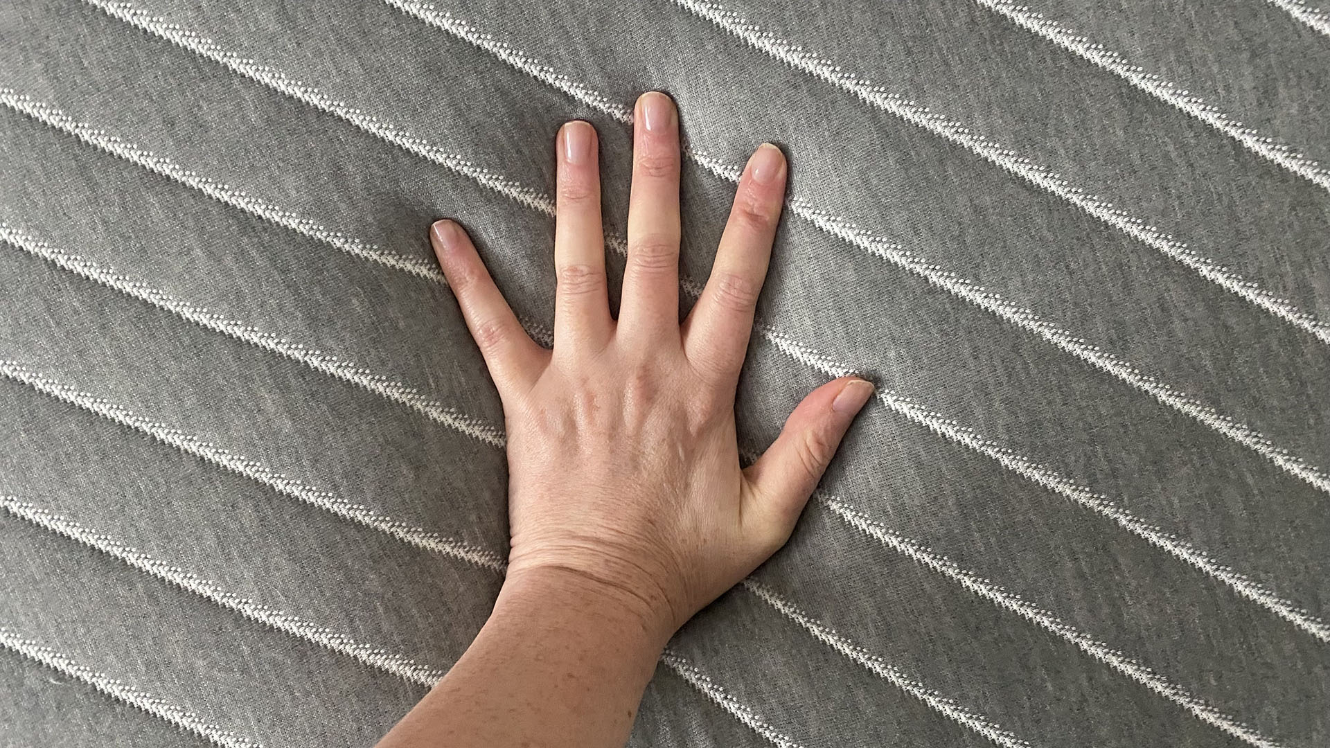 A close up of a hand pushing into the surface of the Siena Memory Foam mattress. The hand is pressing hard to try and making an indentation but it still barely sinks into the mattress.