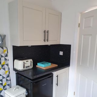 white kitchen with cupboard and black worktop
