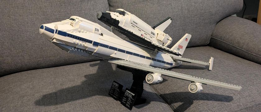 A Lego Icons Shuttle Aircraft Carrier on its stand, the shuttle on the back of the plane. 
