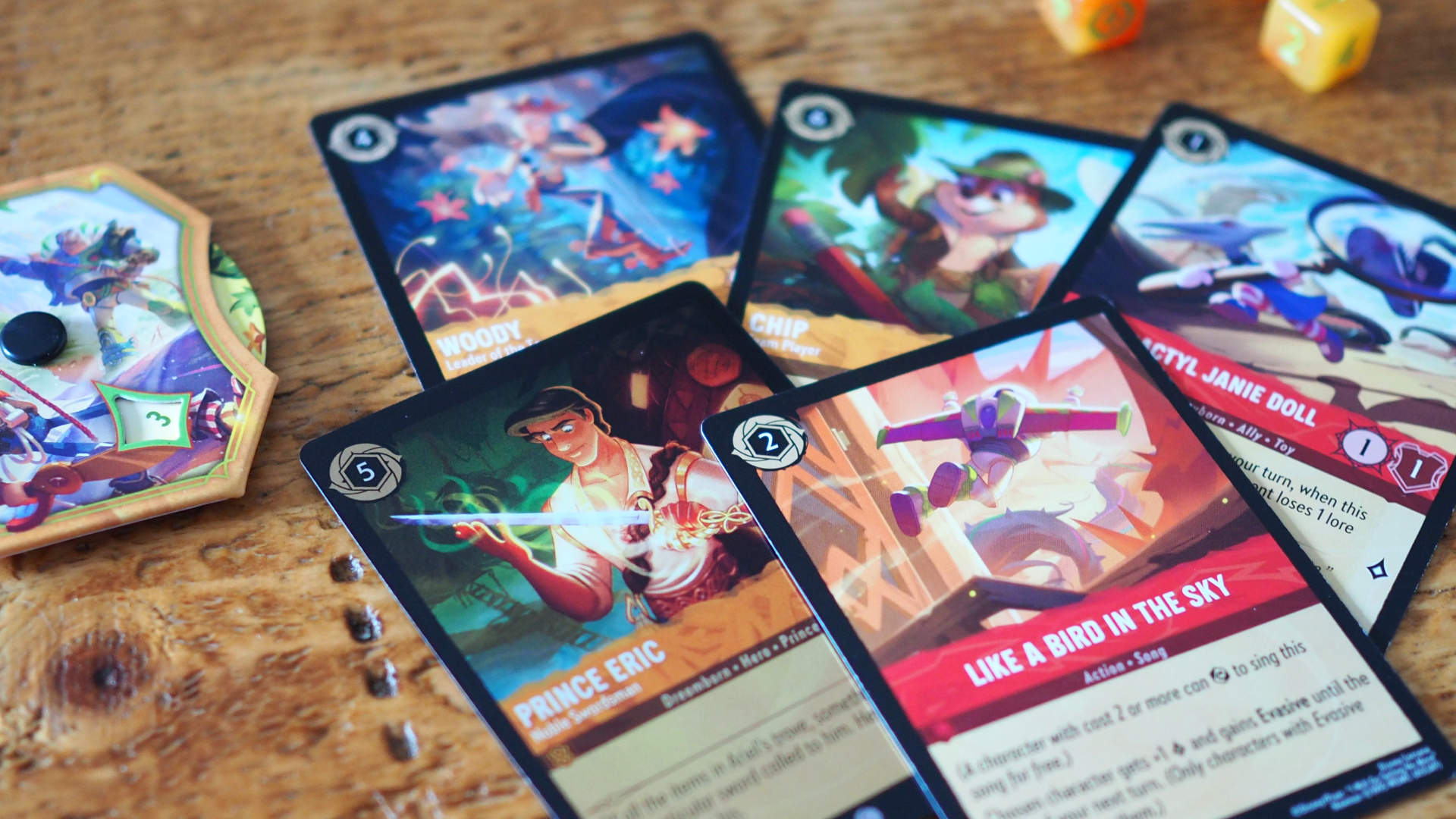 Disney Lorcana Wilds Unknown cards, Lore spinner, and dice on a wooden surface