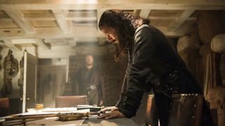 Luke Arnold as Long John Silver in Black Sails, looking at a map