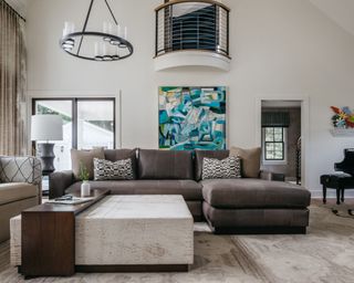 living room with white walls, dark brown sectional and blue abstract artwork on wall