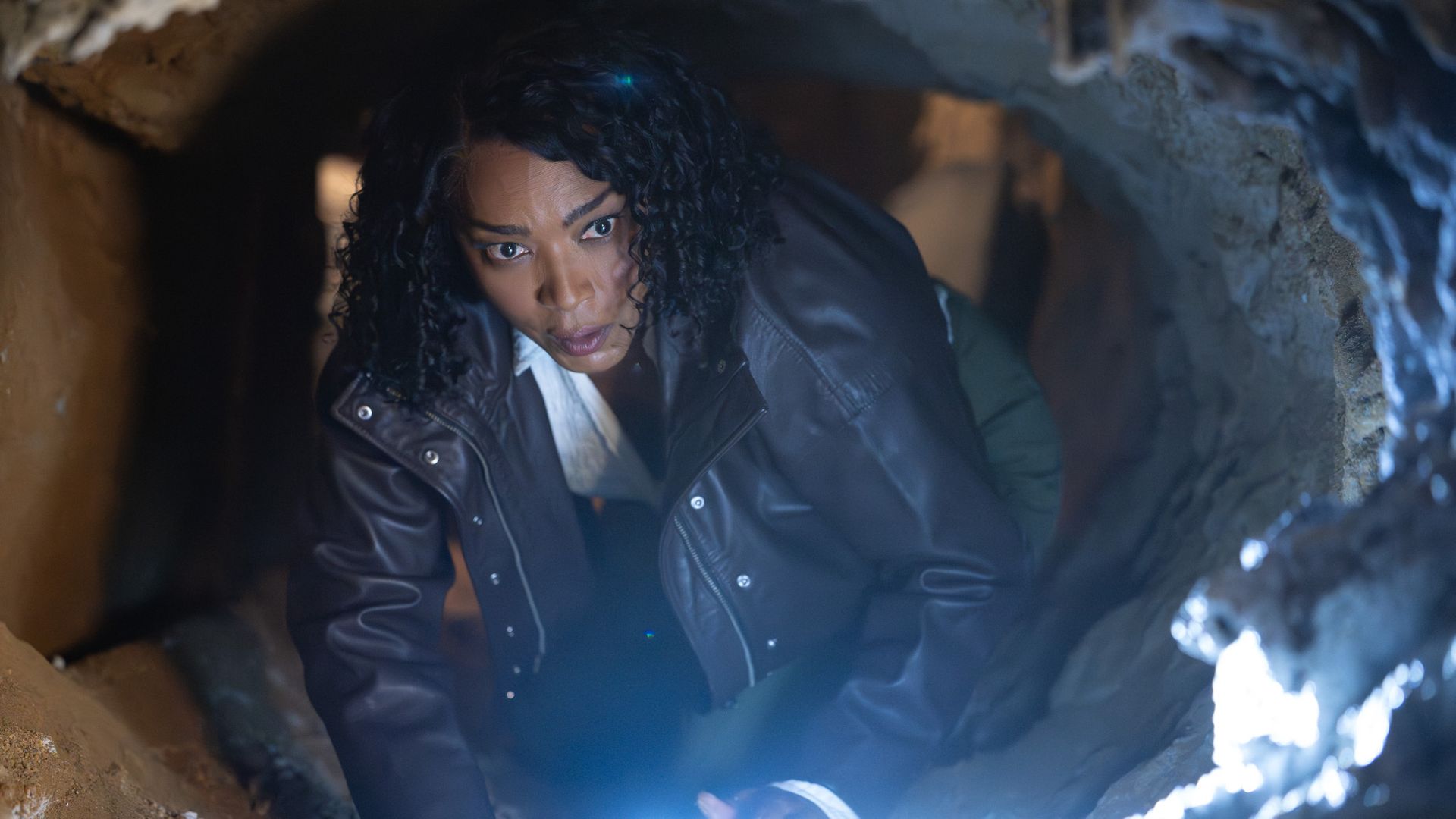 Athena (Angela Bassett) looks curious as she navigates the inside of a crawlspace on 9-1-1.