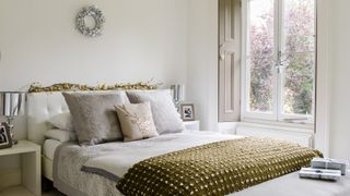 Neutral bedroom with Christmas decorating idea with a garland dressing the headboard and festive cushions on the bed