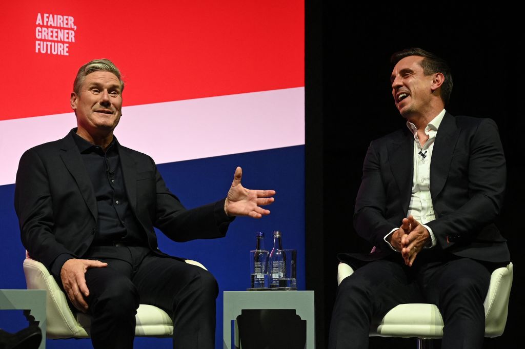 Sir Keir Starmer speaking on stage with a laughing Gary Neville