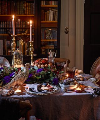 Thanksgiving centerpiece ideas with ornate silver pheasant decoration, candles and foliage centerpiece