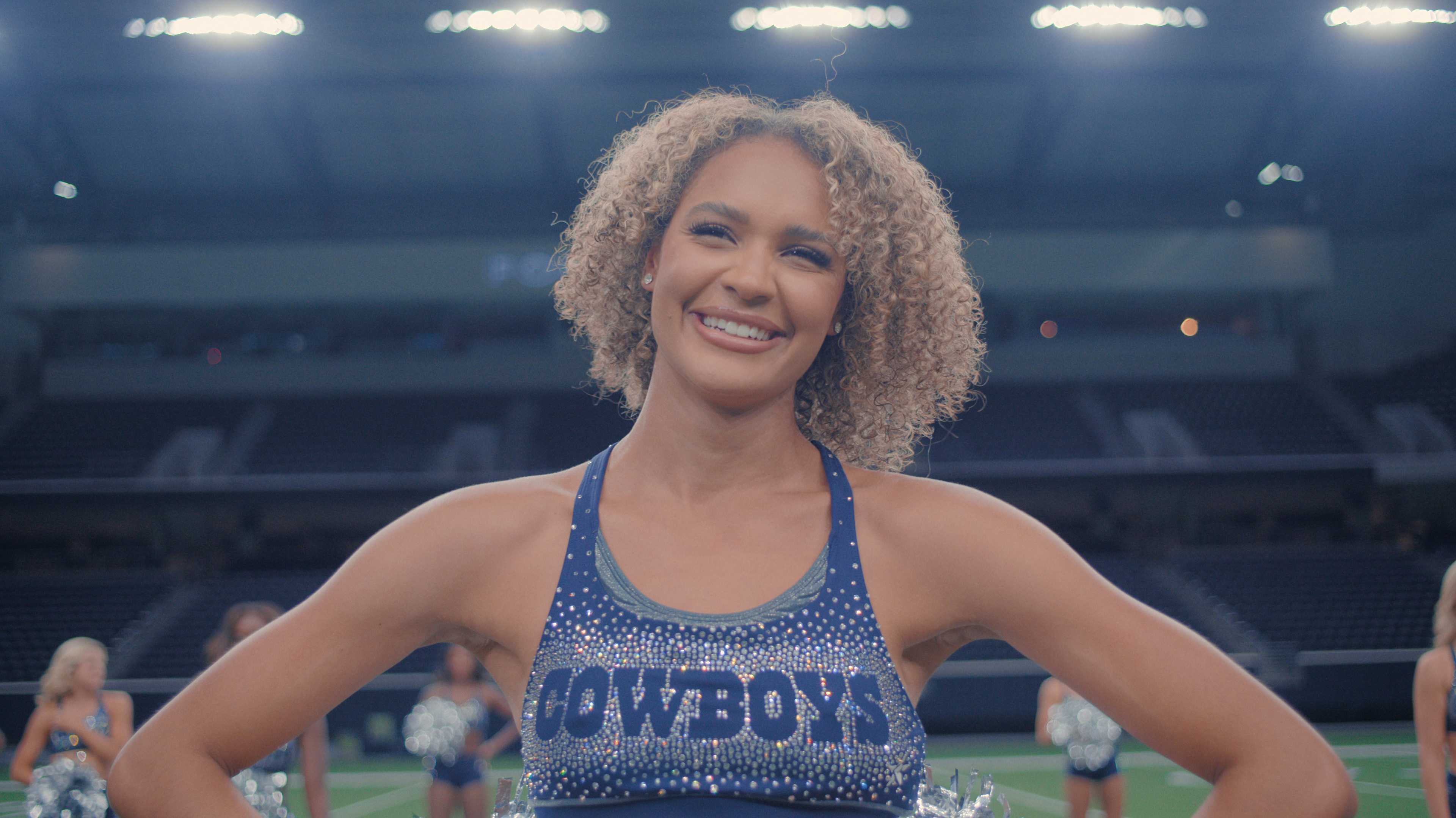 jada mclean smiling with her hands on her hips wearing a cowboys sports bra in america's sweethearts dcc season 2