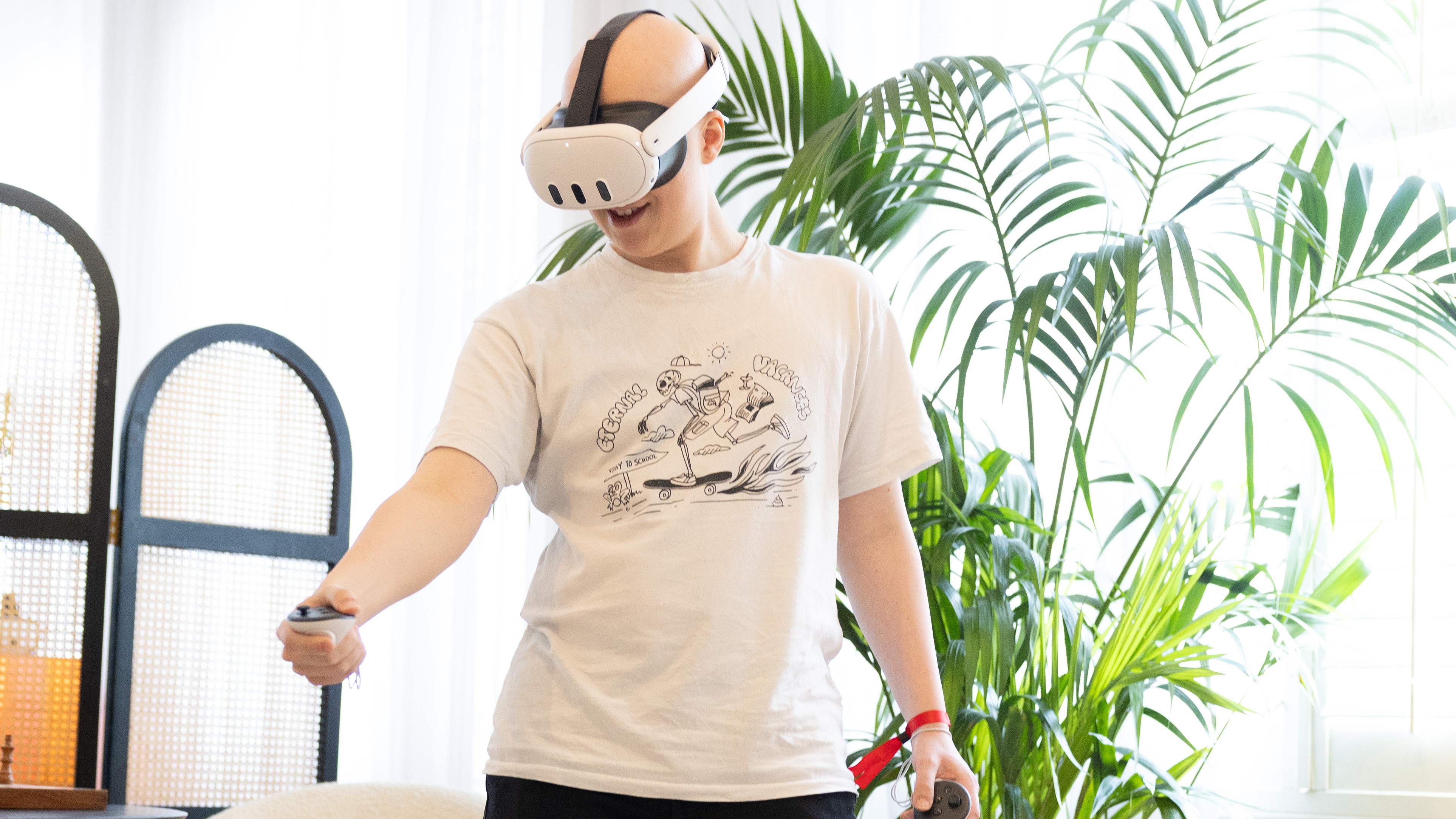 Hamish wearing the Meta Quest 3 as he stands in front of a plant. He's looking at something in VR with wonder.