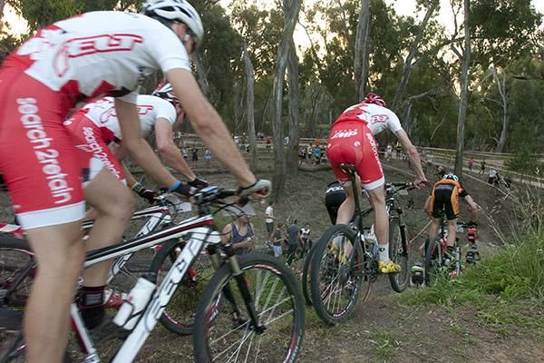 Riders in the men's elite field descend at the back of the course beneath the trees in Shepparton.