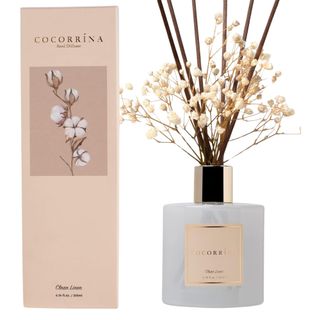 A fresh linen diffuser with white flowers and pink cardboard box packaging