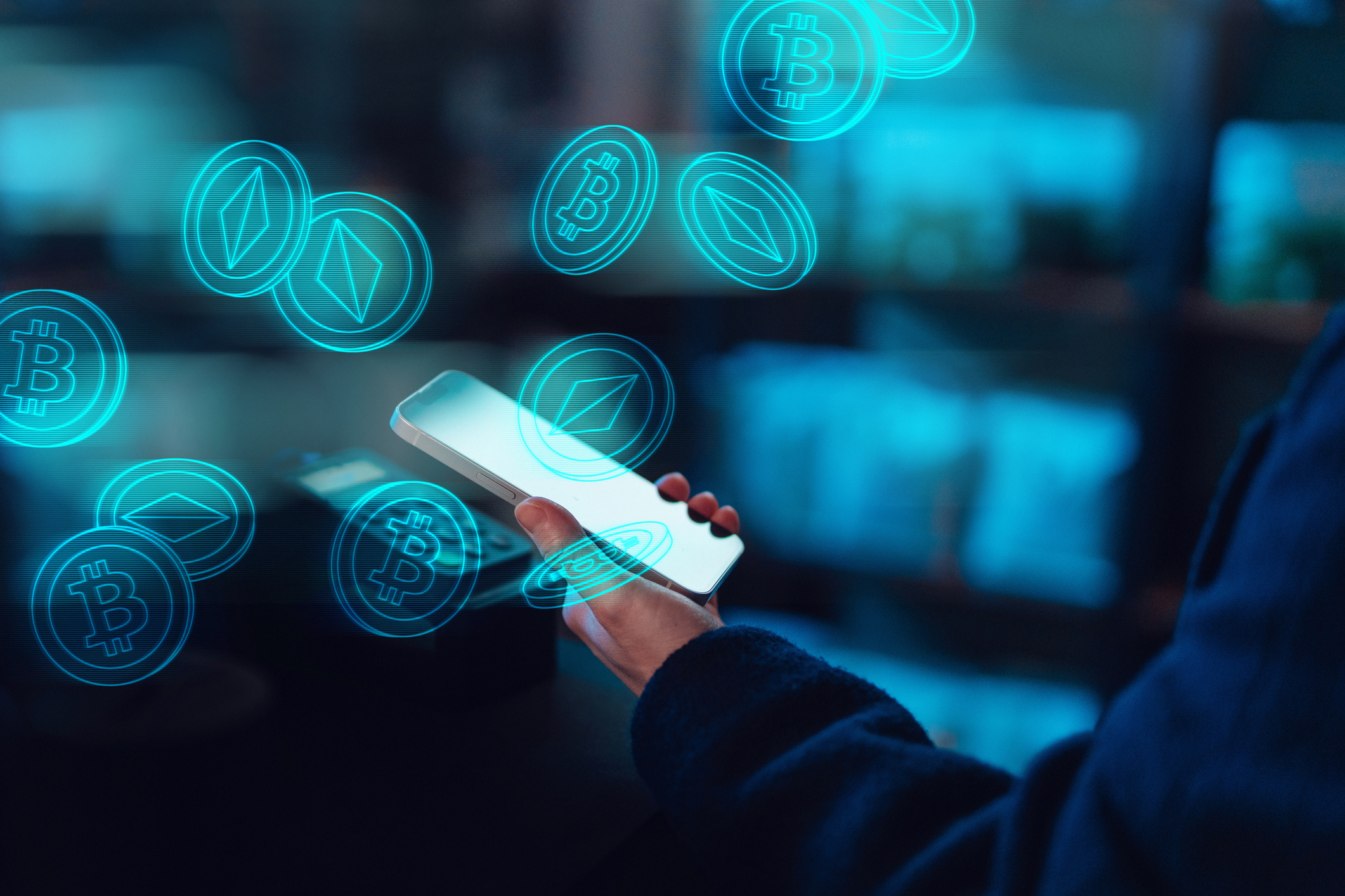 Close-up of female hand using mobile app, investing and trading digital currency on smartphone. Image also includes graphics showing Bitcoin and cryptocurrency logos.