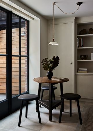 a small table in a beige room next to windows