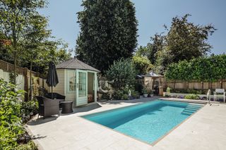 outdoor in ground swimming pool with summer house in garden