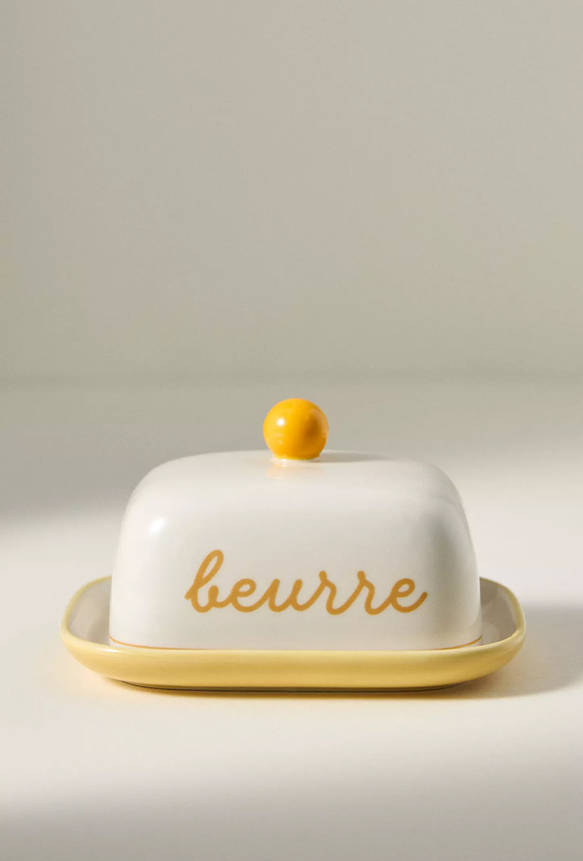 White and yellow butter container with buerre written on it in cursive from Anthropologie