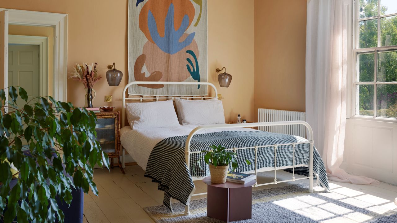 Yellow painted bedroom with cane bedframe, decorative cushions, side table