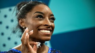 Simone Biles shows off her goat pendant at the Paris Olympics.