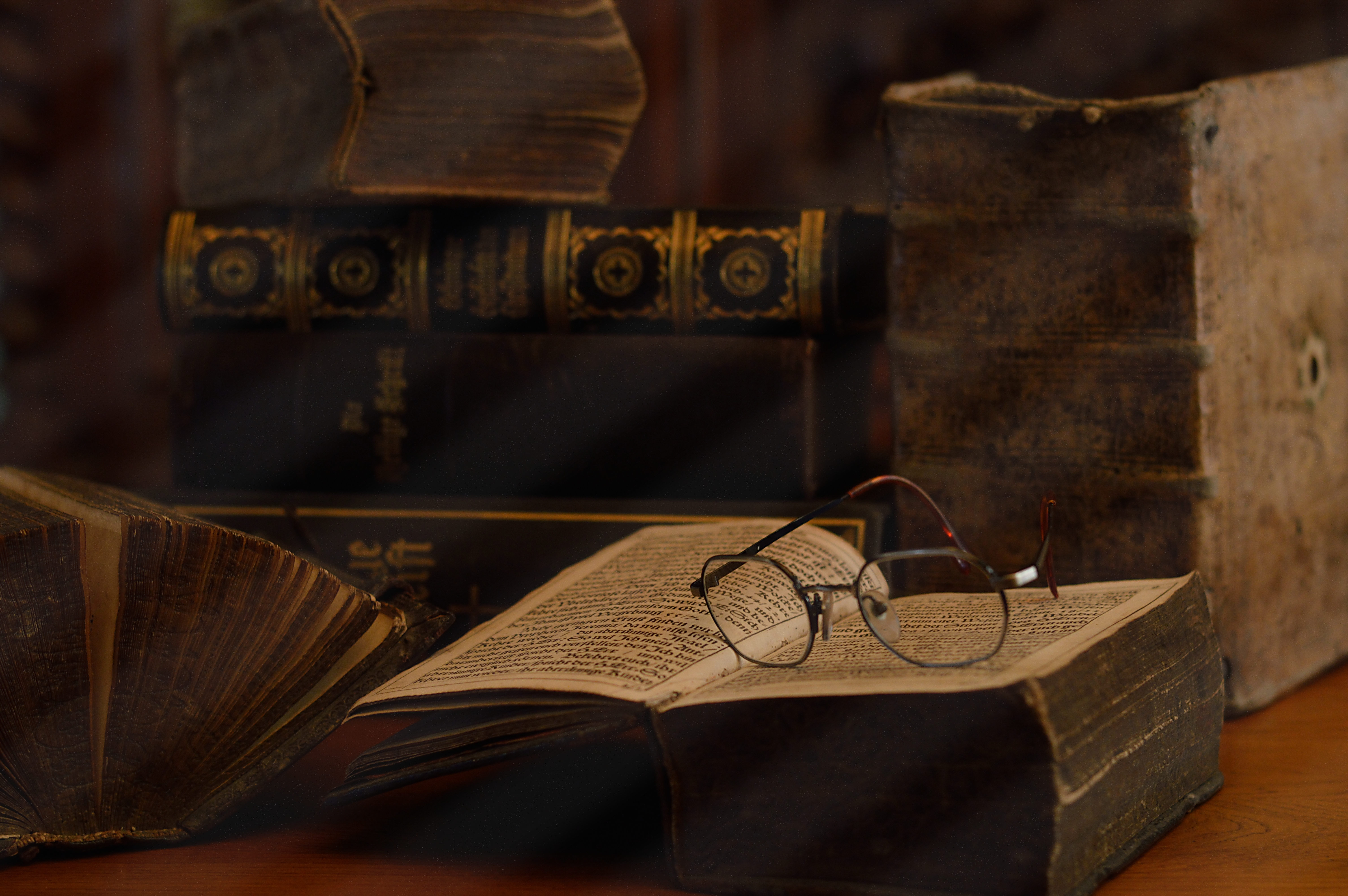 Antique books with reading glasses in a dusty room.
