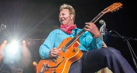 Brian Setzer has some fun as he wears a red neckerchief and plays a round-up orange Gretsch onstage