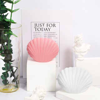 Pair of seashell shaped candles on an aesthetic neutral background