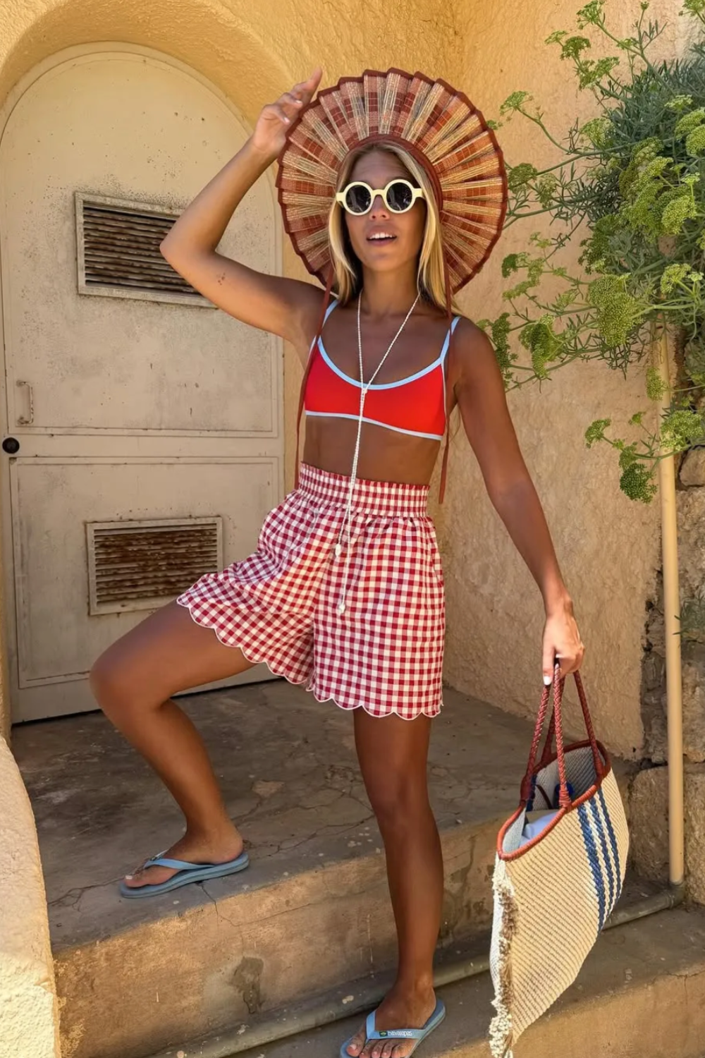 @ritamontezuma draagt een Lorna Murray zonnehoed, een rode gingham-short en een bikinibroekje