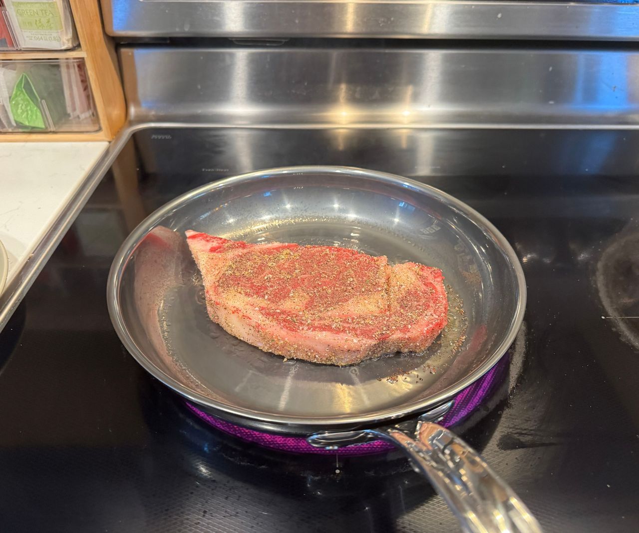 The Hestan NanoBond Skillet frying a steak on a black stovetop