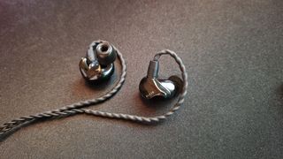 Razer Moray review image Of the earbuds lying on a desk mat with the left earbud facing upward