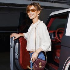 Bella Hadid wearing a pretty white blouse, bootcut jeans, and cap-toe heels