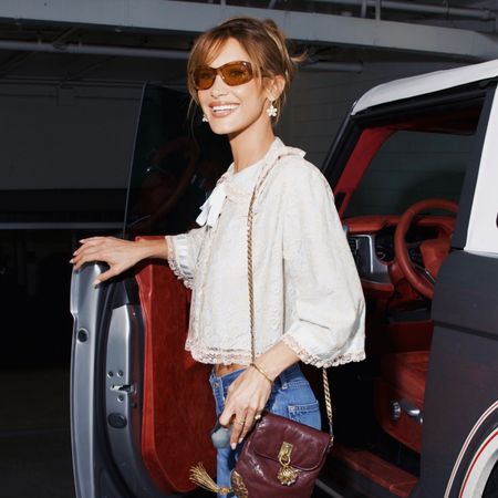 Bella Hadid wearing a pretty white blouse, bootcut jeans, and cap-toe heels