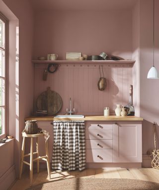 kitchen with pink walls and cabinetry and wooden floor with rug and open shelf