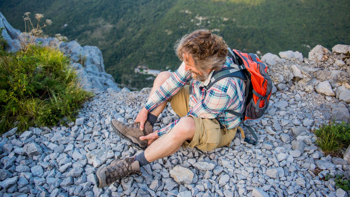 A hiker holds his ankle after hurting it on the trail