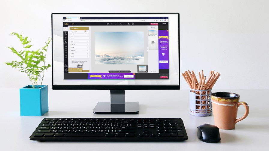 En skjerm stående på en minimalistisk kontorpult med Fotor kjørende