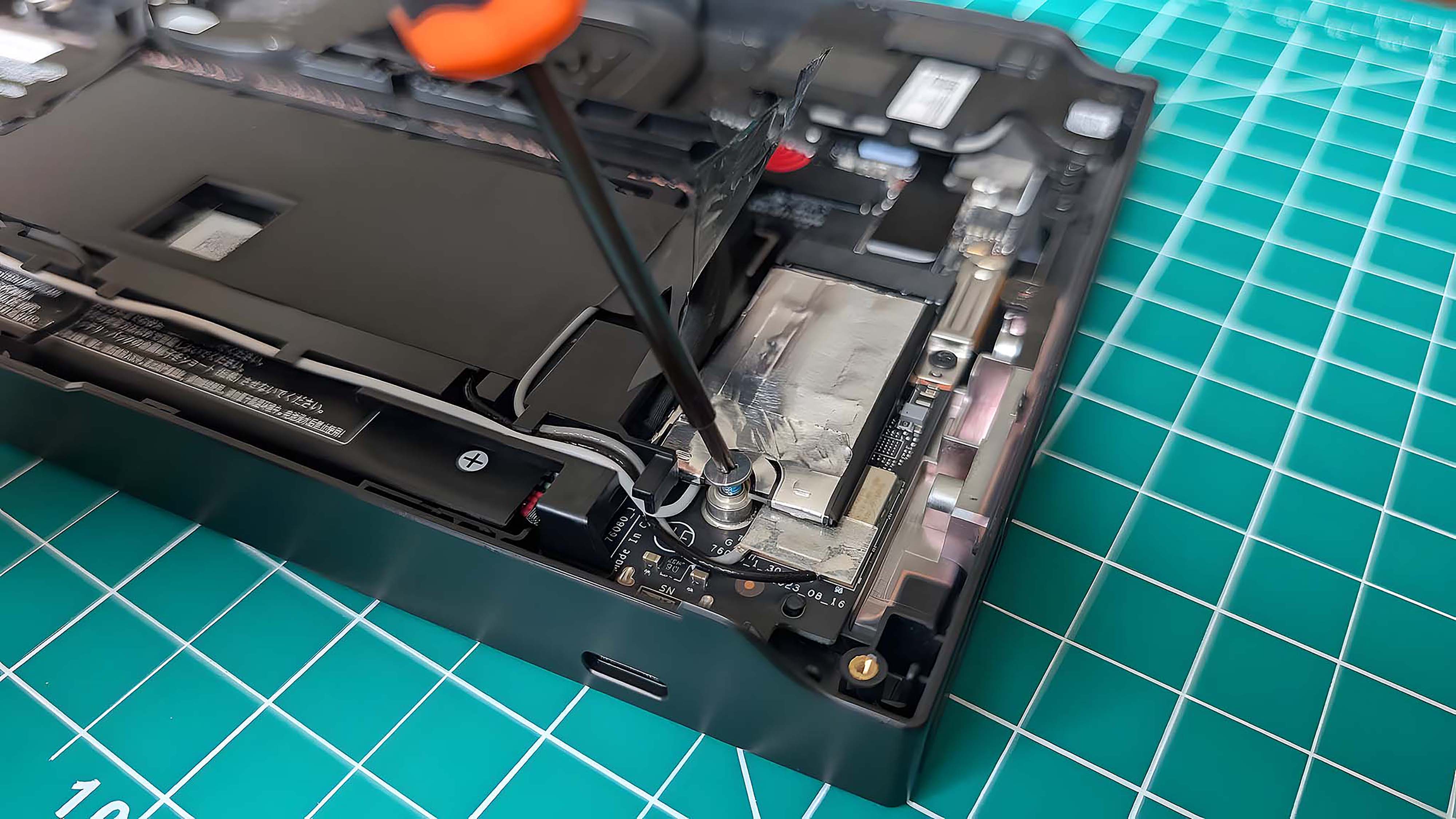 A screw driver unscrewing the original Lenovo Legion Go SSD screw.