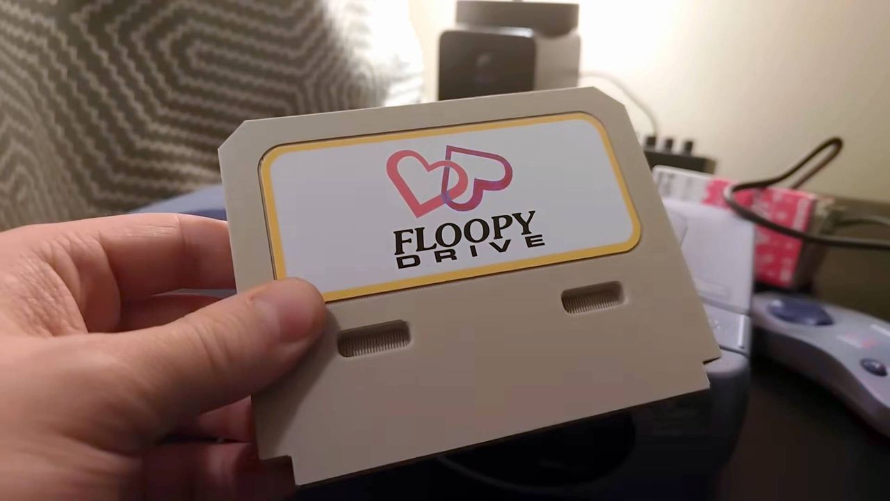 Hand holding Casio Loopy "Floopy Drive" flash cart with custom label.