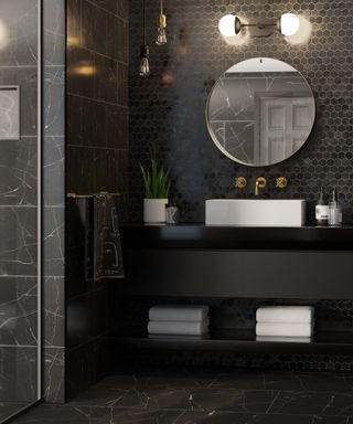 Black bathroom with tiled shower area and hexagonal tiled backsplash and wall lights, pendant lights and wall-hung furniture