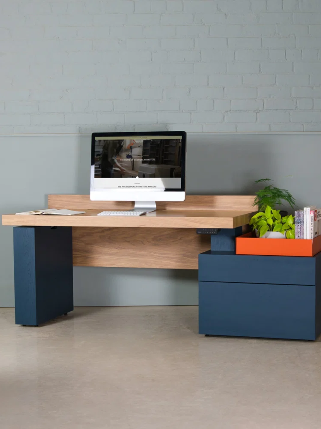 A wood sit-stand desk from Koda with a blue and orange storage space