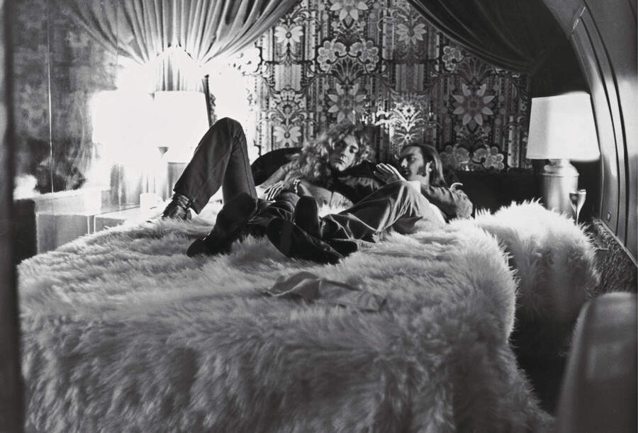 Robert Plant (L) of the band Led Zeppelin and the group's road manager, Richard Cole, relax on a bed covered by a fur rug and discuss details of their upcoming concert, New York City, New York, July 30, 1973.