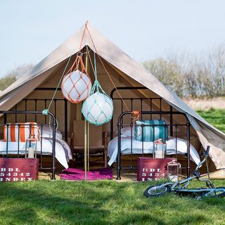 outdoor off-white tent with beds and bicycle