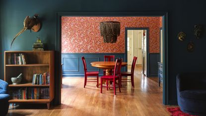 Shot from living room to dining room with dark blue trim and red wallpaper