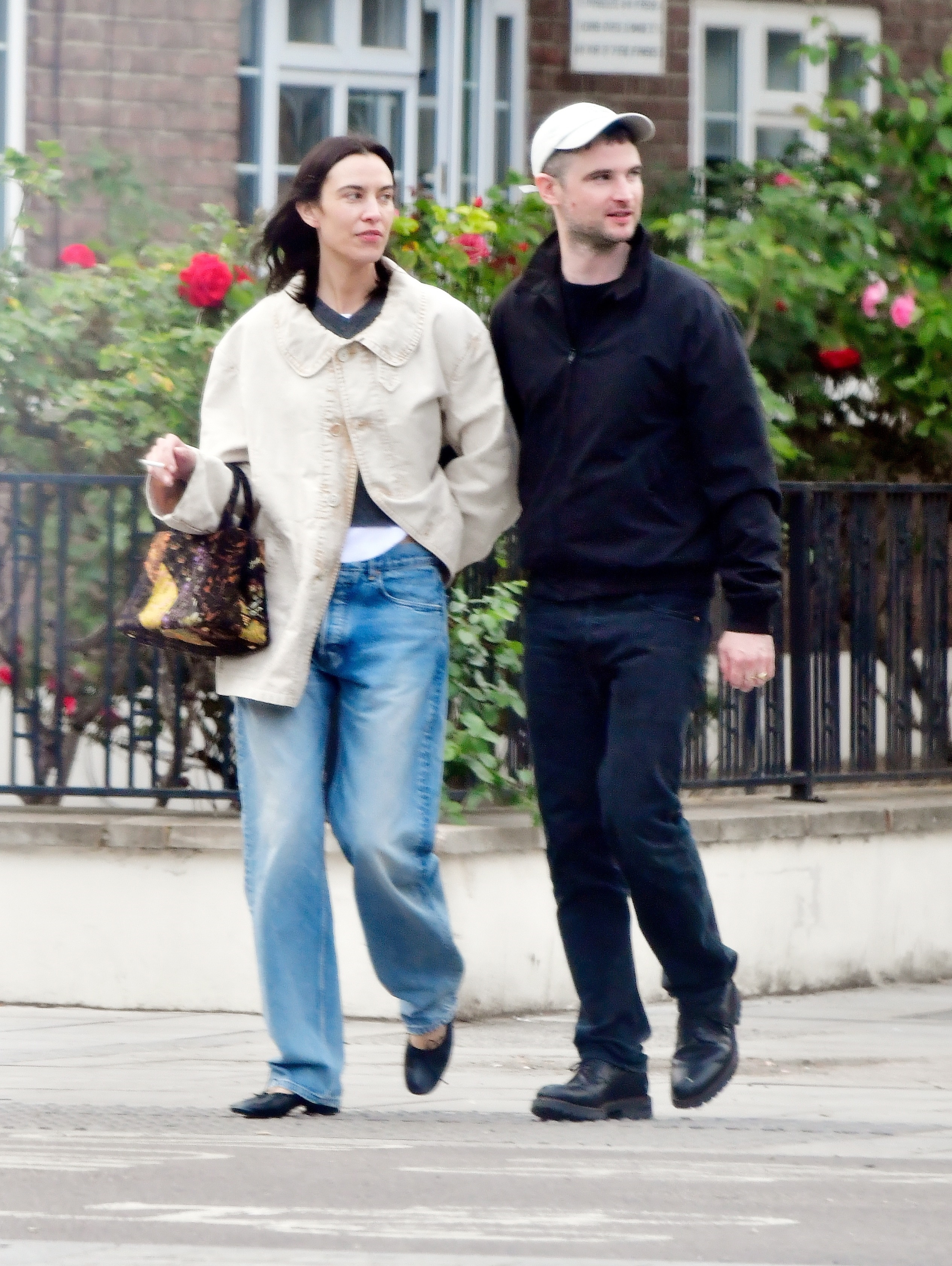 Alexa Chung walks down the street wearing blue jeans with black ballet pumps and a cream jacket.