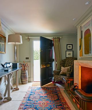 Well lit hallways ideas shown here with a vintage rug and lit fire opposite a console table.