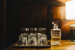 A tray of drinking glasses with a crystal whiskey decanter