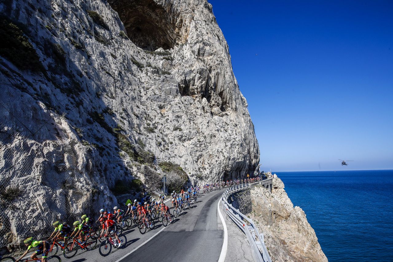 The peloton sweep along the coastal road.