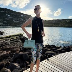 Elsa Hosk wearing a black halter top, printed capri leggings, and criss-cross sandals